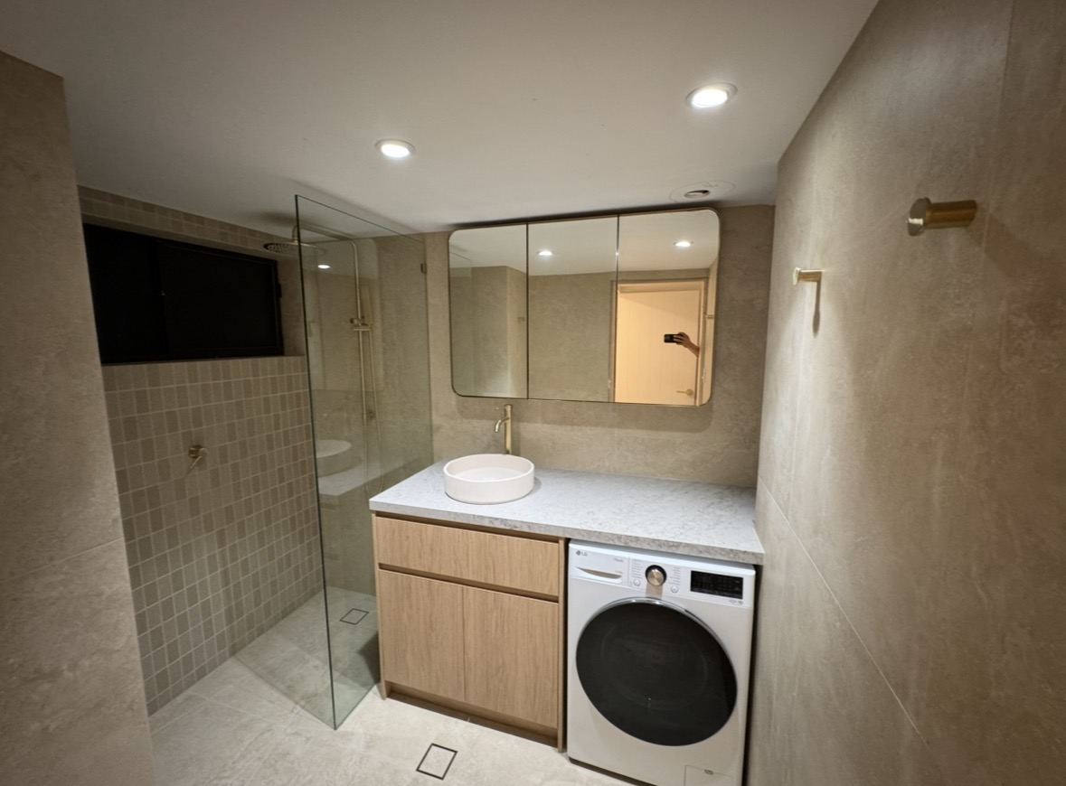 Combined bathroom and laundry with stone benchtop, timber cabinetry and brass fittings